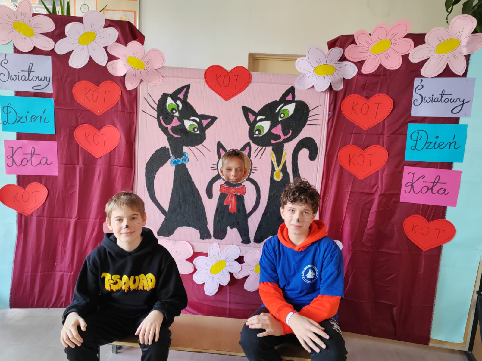 Uczniowie na tle plakatu z dnia kota